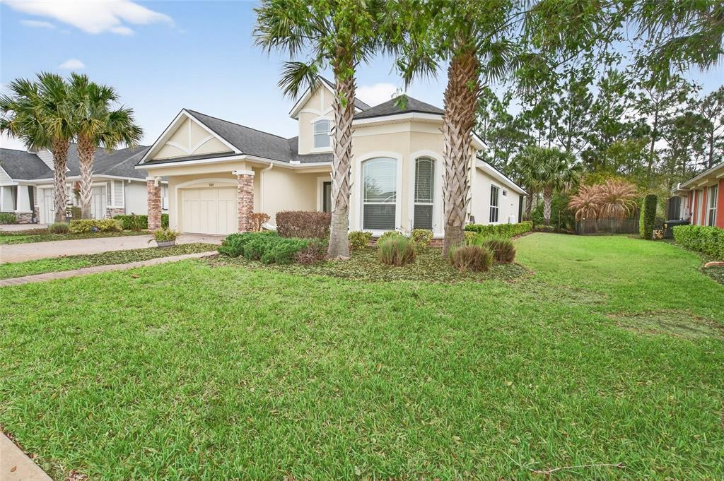 A single-story house with a beige exterior, a two-car garage, and palm trees in front — 349 CHELSEA PLACE AVENUE, ORMOND BEACH, FL