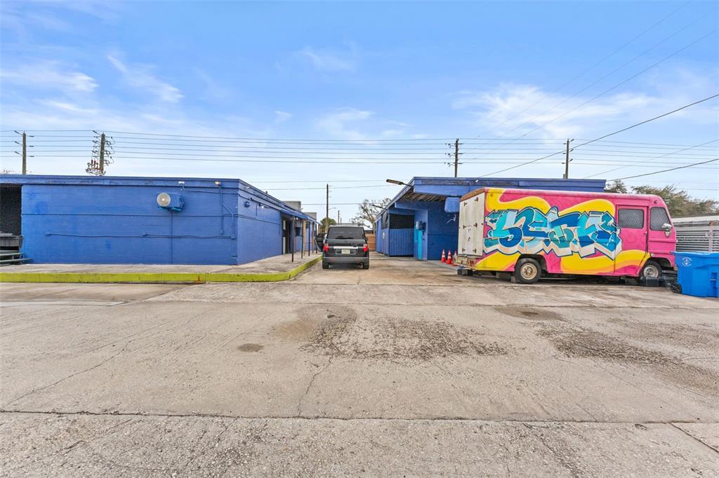 A paved lot sits between two blue industrial buildings with a parked van and SUV — 701 49TH STREET S, GULFPORT, FL