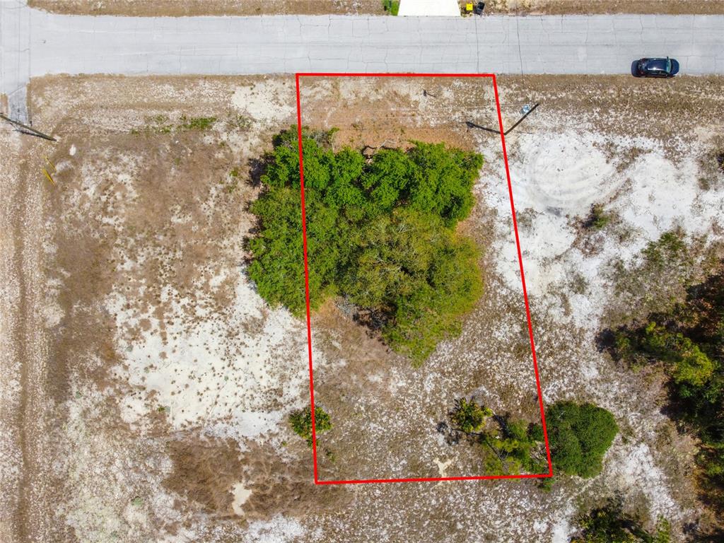 An aerial view shows a rectangular vacant lot outlined in red next to a road — 1344 HILLSBOROUGH COURT, KISSIMMEE, FL