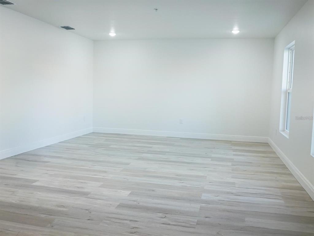 An empty room features white walls, recessed lighting, and light-colored wood-look flooring — 2201 CONWAY DRIVE UNIT 203, DELTONA, FL