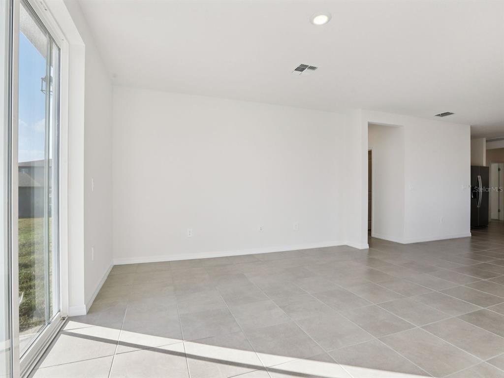 An empty room with white walls, tile flooring, and a sliding glass door — 11337 BELLEWOOD TERRACE, PARRISH, FL