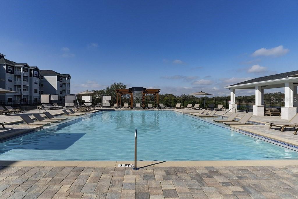 A rectangular swimming pool with lounge chairs sits on a paved deck near apartment buildings — 1015 LAKE FOREST BOULEVARD UNIT A2, WINTER HAVEN, FL