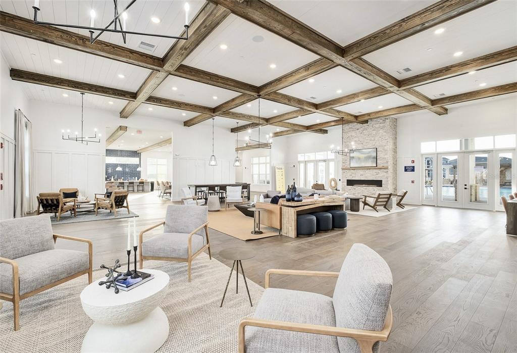 A spacious, open-concept community clubhouse features wood-beamed ceilings, a stone fireplace, and modern lounge seating — 1015 LAKE FOREST BOULEVARD UNIT A2, WINTER HAVEN, FL