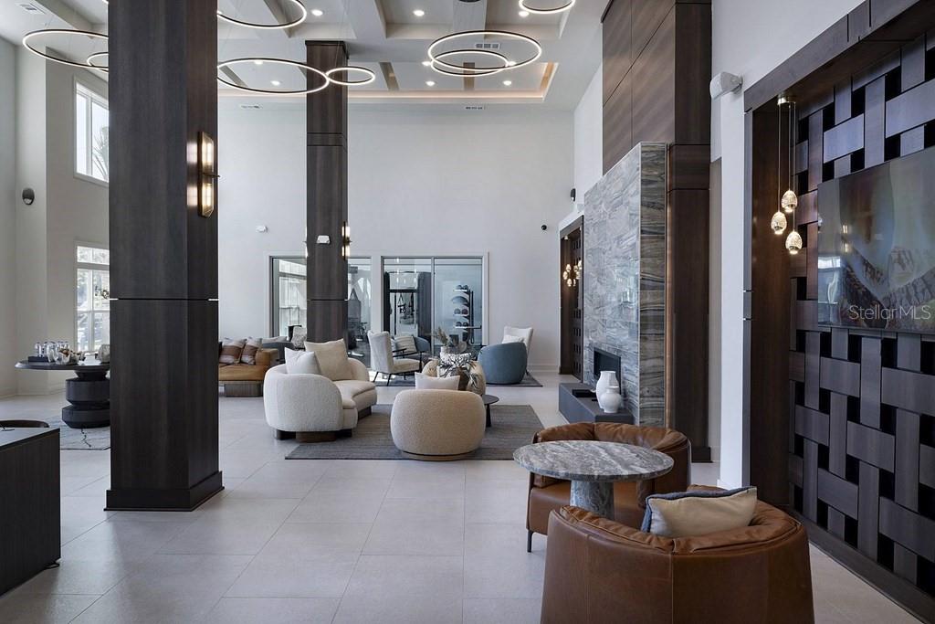 A modern, high-ceilinged lobby features dark wood columns, stone fireplace accents, and contemporary circular lighting — 1015 LAKE FOREST BOULEVARD UNIT A2, WINTER HAVEN, FL