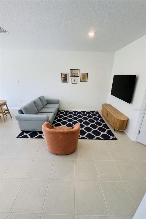 A living room features a light blue sofa, an orange chair, and a wall-mounted television — 3035 MINDFULLNESS DRIVE, CLERMONT, FL
