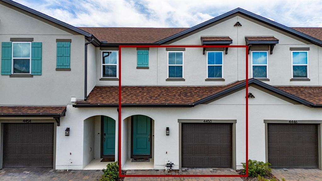 The exterior of a two-story townhouse features a brown garage door and a teal front door — 4450 SMALL CREEK ROAD, KISSIMMEE, FL