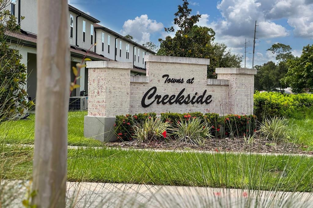 A brick monument sign for Towns at Creekside stands in front of a residential building — 4450 SMALL CREEK ROAD, KISSIMMEE, FL