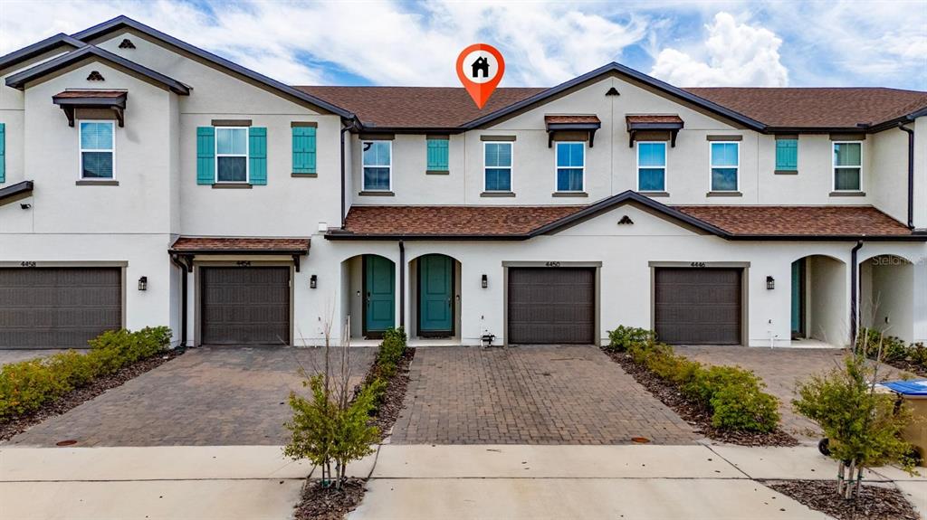 A row of two-story townhomes with brown garage doors and teal front doors — 4450 SMALL CREEK ROAD, KISSIMMEE, FL