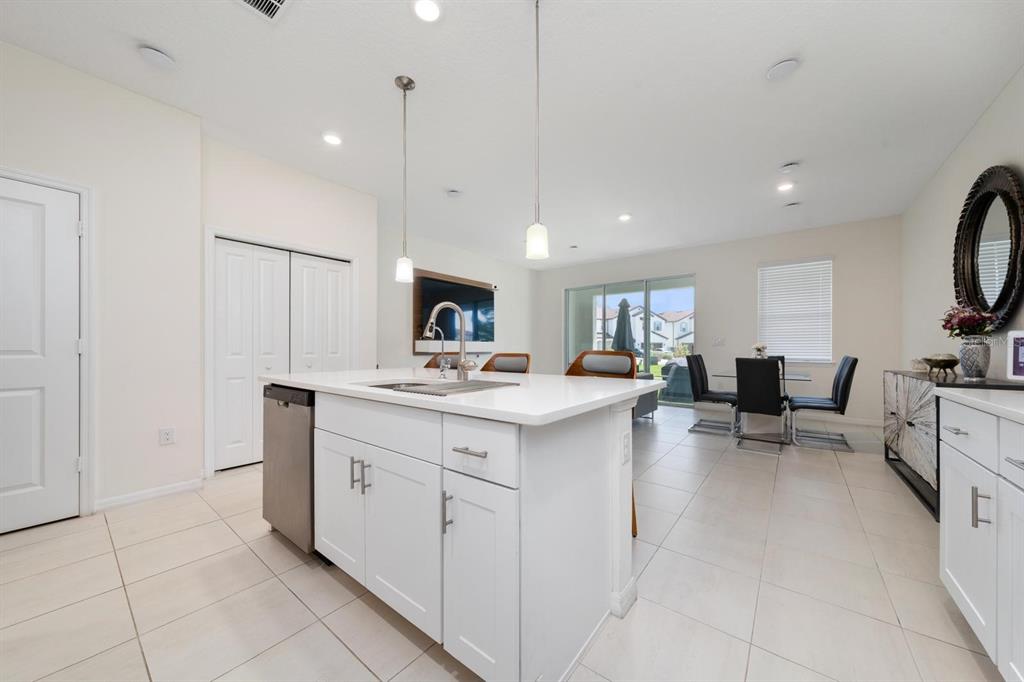 A bright kitchen features a white island with a sink, stainless dishwasher, and tile flooring — 4450 SMALL CREEK ROAD, KISSIMMEE, FL