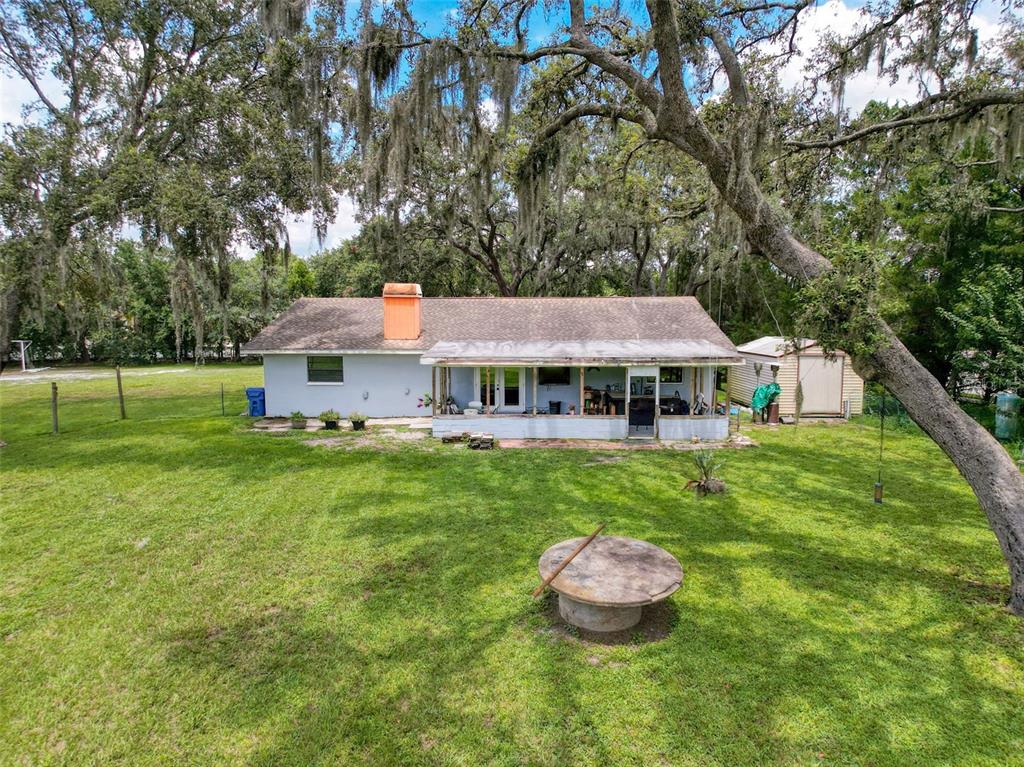 A backyard view of a single-story house with a screened porch and a detached shed — 15438/15440 AZRA DR, ODESSA, FL