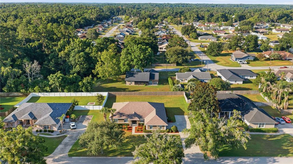 An aerial view shows three suburban houses with driveways and lawns in a residential neighborhood — 4460 SE 106TH STREET, BELLEVIEW, FL