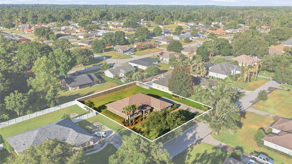 An aerial view shows a single-story house with a fenced backyard in a suburban neighborhood — 4460 SE 106TH STREET, BELLEVIEW, FL