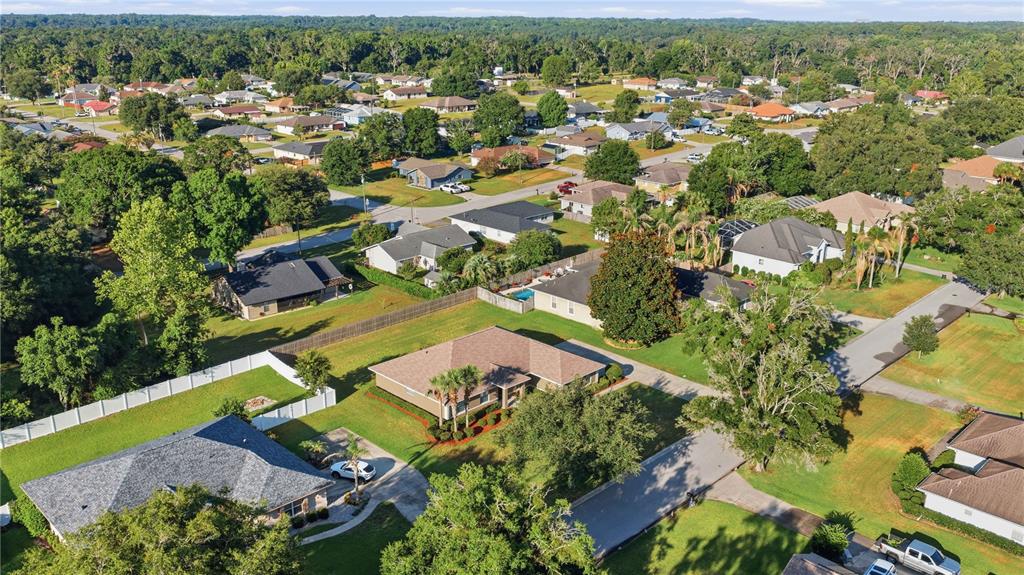 An aerial view shows a suburban neighborhood with single-family homes, green lawns, and mature trees — 4460 SE 106TH STREET, BELLEVIEW, FL