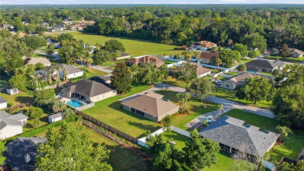 An aerial view of a suburban neighborhood featuring single-family homes with pools and green lawns — 4460 SE 106TH STREET, BELLEVIEW, FL