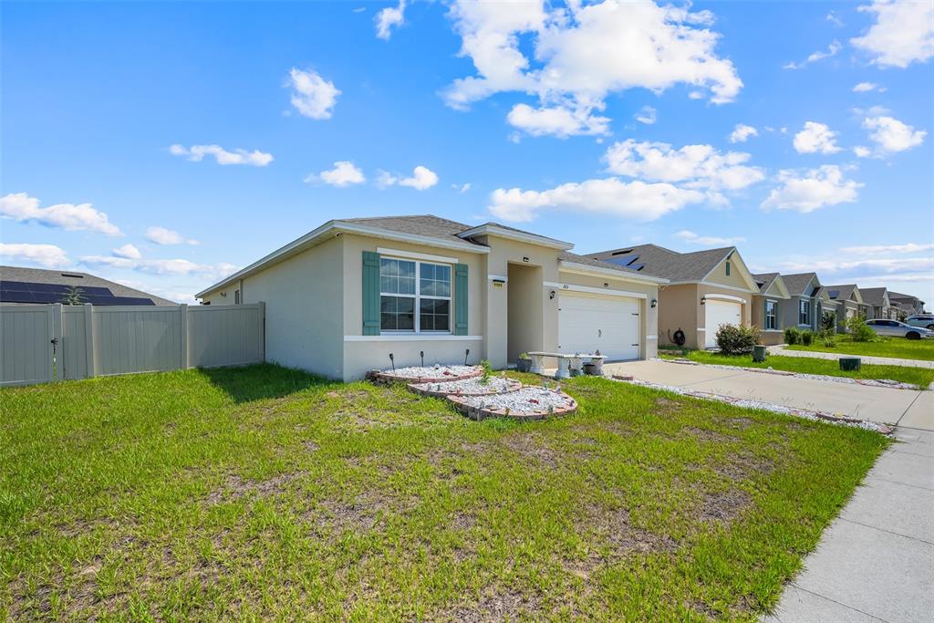 A single-story suburban house with a tan exterior, teal shutters, and a concrete driveway — 1105 TORRENTE LANE, HAINES CITY, FL