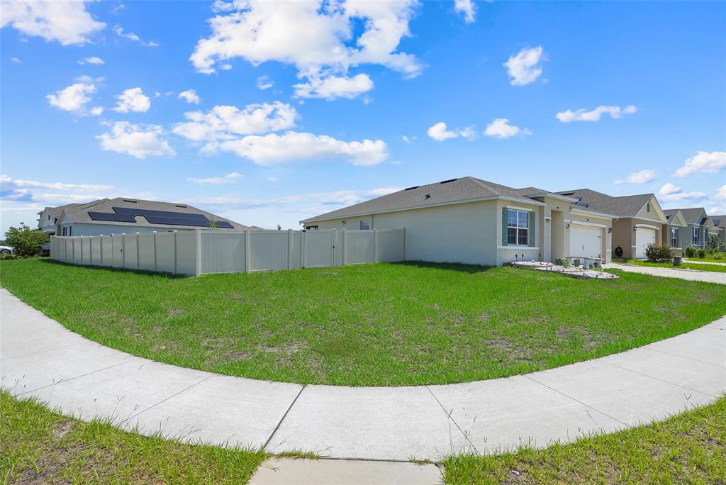 A single-story house with a white vinyl fence and a green lawn on a corner lot — 1105 TORRENTE LANE, HAINES CITY, FL