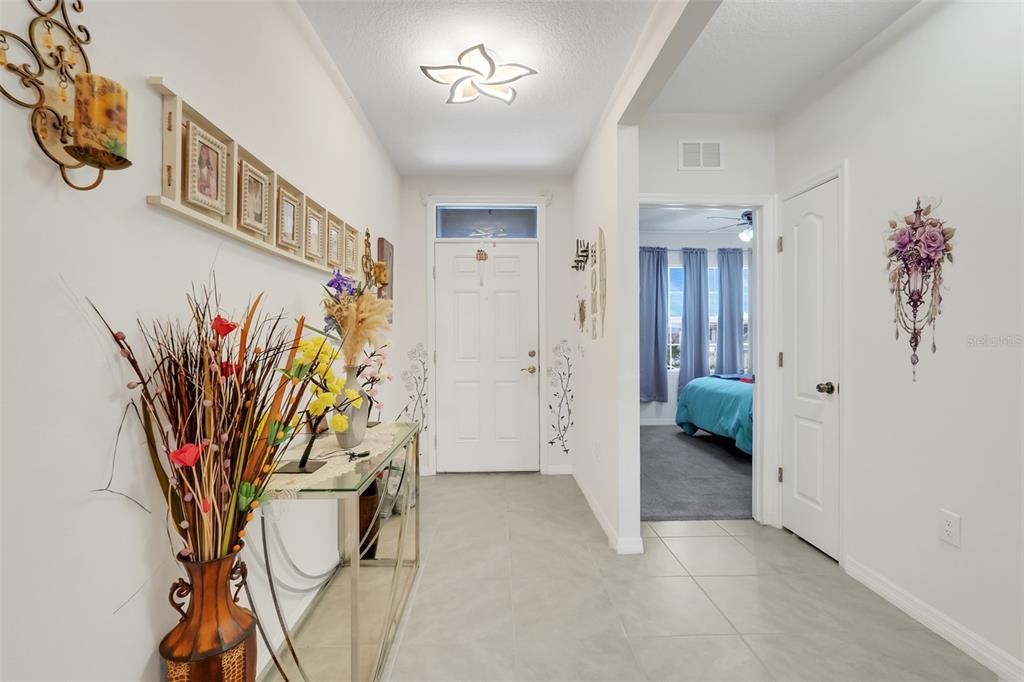 A tiled entryway features a console table, wall decor, and a view into a bedroom — 1105 TORRENTE LANE, HAINES CITY, FL