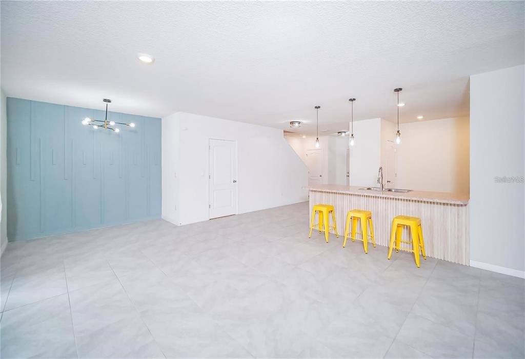 A room with light gray tile floors, a blue accent wall, and a kitchen island — 9039 ALBA LANE, KISSIMMEE, FL