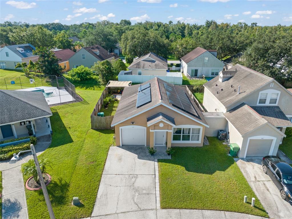 An aerial view shows a tan suburban house with solar panels on the roof — 338 WINDFORD COURT, WINTER GARDEN, FL
