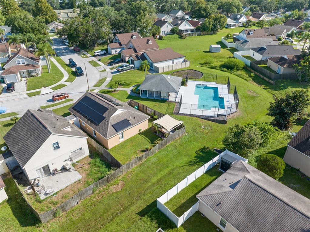 An aerial view shows suburban houses, a community pool, and fenced backyards on a sunny day — 338 WINDFORD COURT, WINTER GARDEN, FL