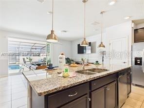 A kitchen island with granite countertops sits in front of a living area and pool — 3806 LANA AVENUE, DAVENPORT, FL