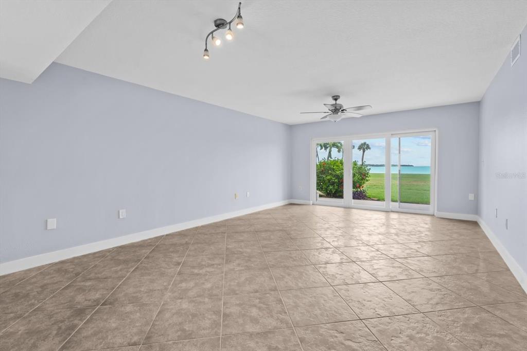 An empty room with light blue walls, tile flooring, a ceiling fan, and sliding glass doors — 7530 SUNSHINE SKYWAY LANE S UNIT T30, ST PETERSBURG, FL