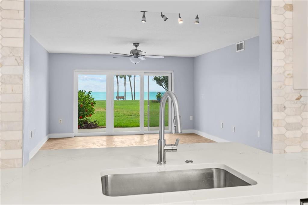 A kitchen sink overlooks a living area with sliding glass doors leading to a waterfront view — 7530 SUNSHINE SKYWAY LANE S UNIT T30, ST PETERSBURG, FL