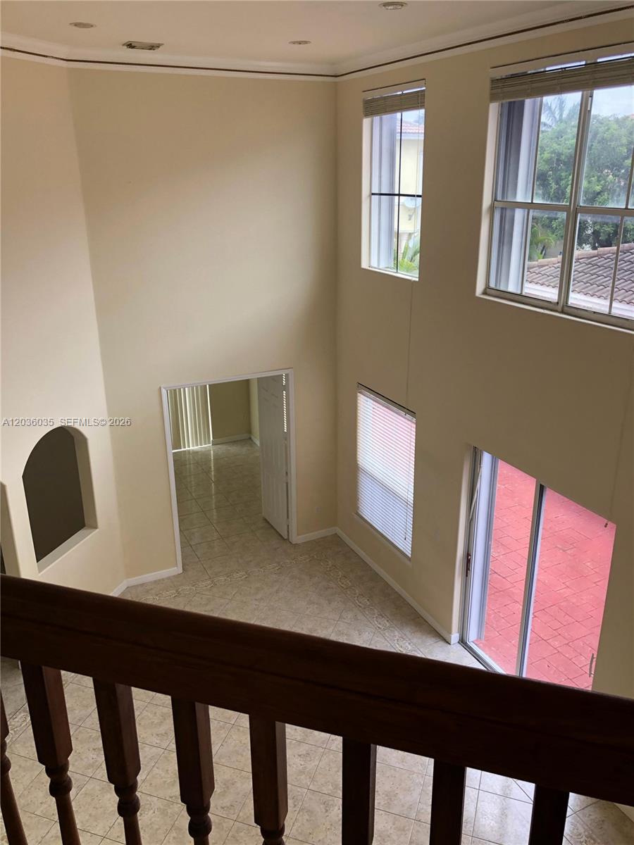 A high-ceilinged living area features tile flooring, a wooden railing, and large windows — 11253 NW 47th Ln, Doral FL 33178, DORAL, FL