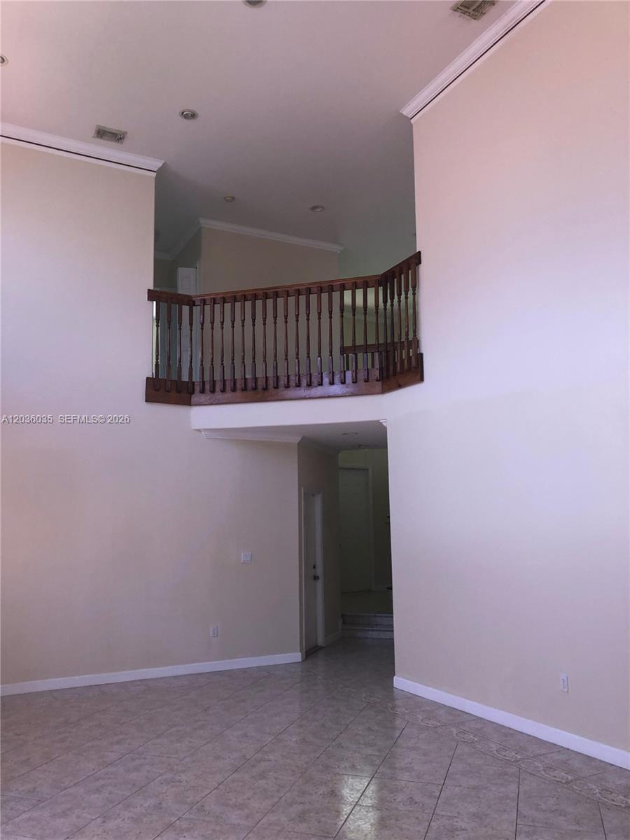 A high-ceilinged room features light-colored tile flooring and a wooden balcony overlooking the space — 11253 NW 47th Ln, Doral FL 33178, DORAL, FL