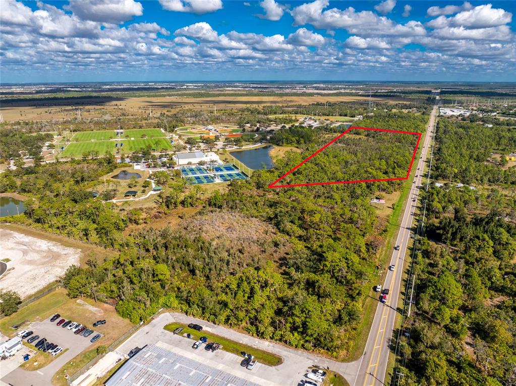 An aerial view shows a wooded plot of land outlined in red next to a road — 0 RIVER ROAD, ENGLEWOOD, FL