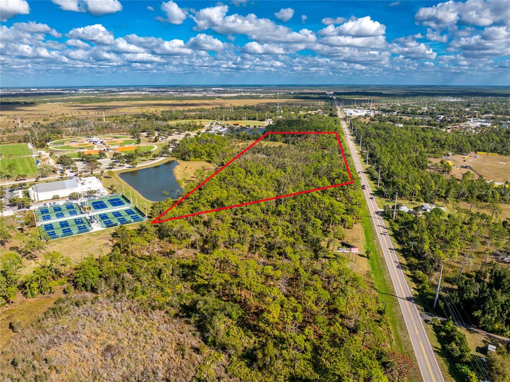 An aerial view shows a wooded plot of land outlined in red next to a road — 0 RIVER ROAD, ENGLEWOOD, FL