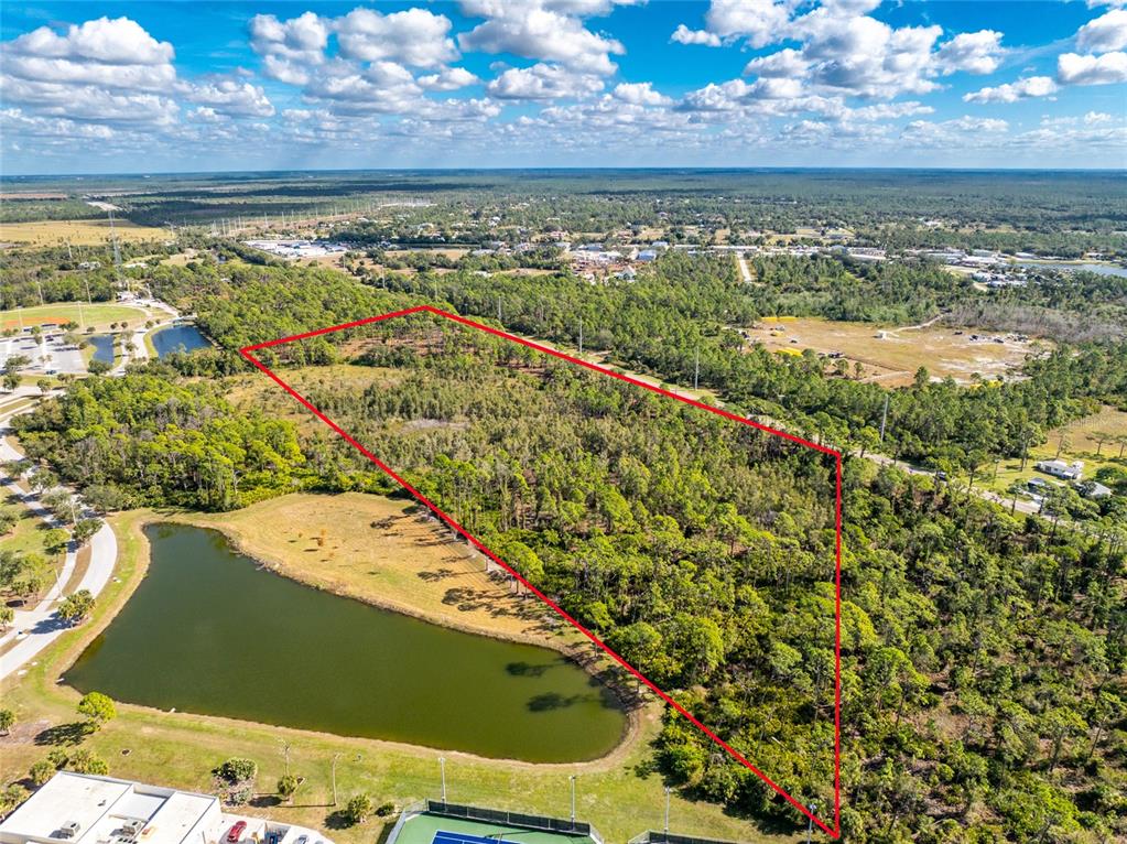 An aerial view shows a wooded plot of land outlined in red near a pond — 0 RIVER ROAD, ENGLEWOOD, FL
