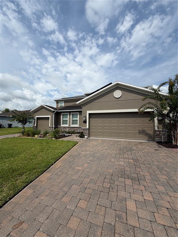 A two-story suburban house with a paved driveway, solar panels, and a grassy front yard — 491 BRUNSWICK DRIVE, DAVENPORT, FL