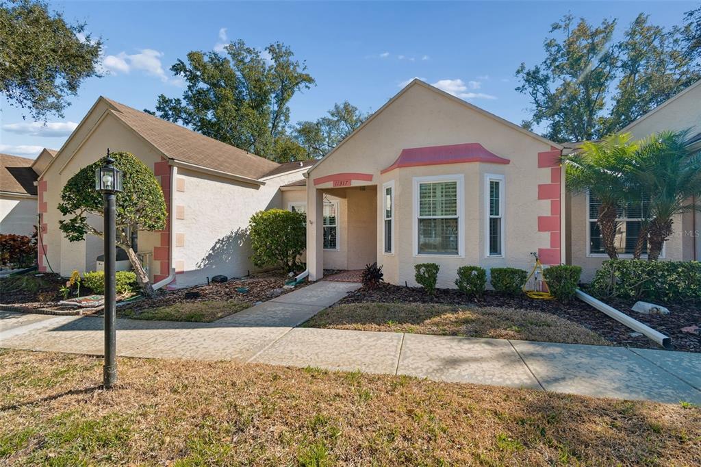 A single-story stucco house with a tan exterior, pink accents, and a front walkway — 11317 VERSAILLES LANE UNIT 5, PORT RICHEY, FL