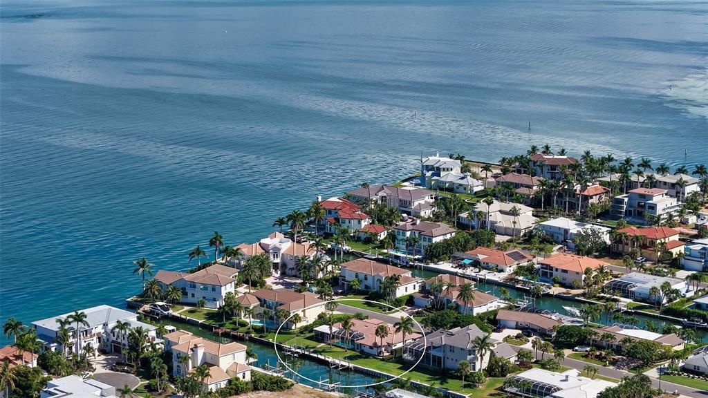An aerial view shows a waterfront residential neighborhood with a circled house on a canal — 595 BOWSPRIT LANE, LONGBOAT KEY, FL