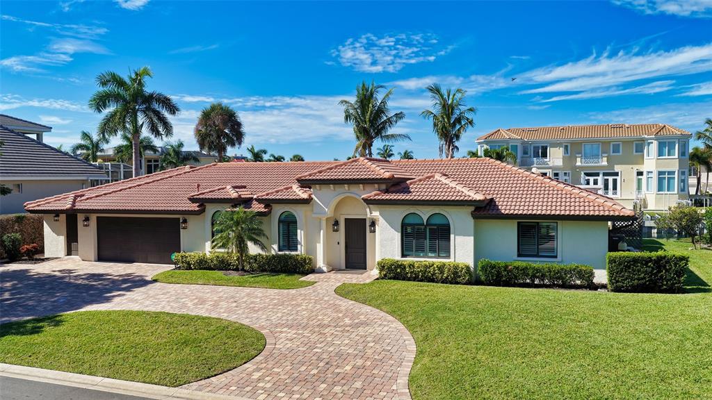 A single-story house with a terracotta tile roof, stucco exterior, and a paved driveway — 595 BOWSPRIT LANE, LONGBOAT KEY, FL
