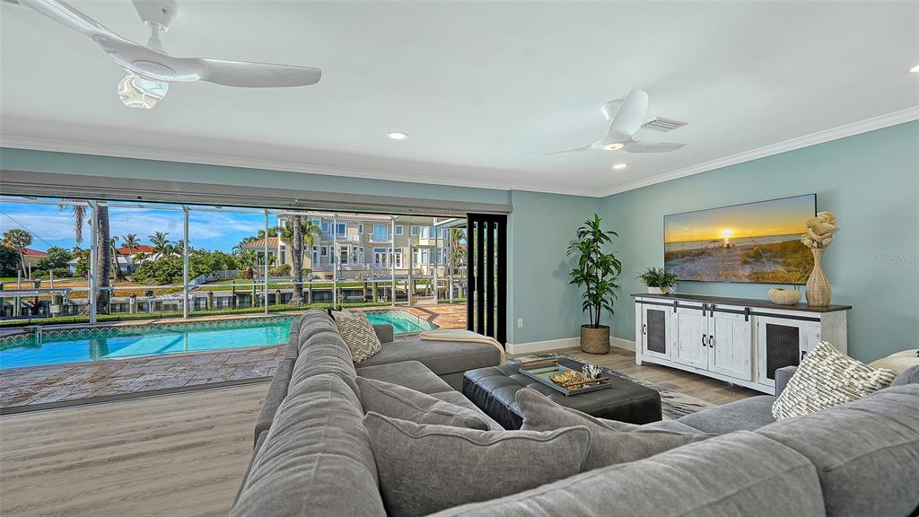 A living room with a sectional sofa faces a television, pool, and canal view — 595 BOWSPRIT LANE, LONGBOAT KEY, FL