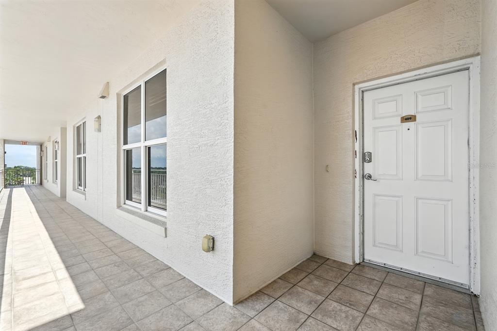 A white door labeled 409 sits at the end of a tiled outdoor apartment hallway — 2403 S ATLANTIC AVENUE UNIT 409, DAYTONA BEACH SHORES, FL