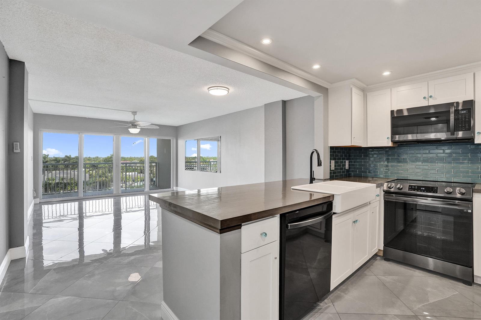 A kitchen with white cabinets, a dark wood island, and a view of a balcony — 2611 N Riverside Drive # 604, Pompano Beach FL 33062, POMPANO BEACH, FL