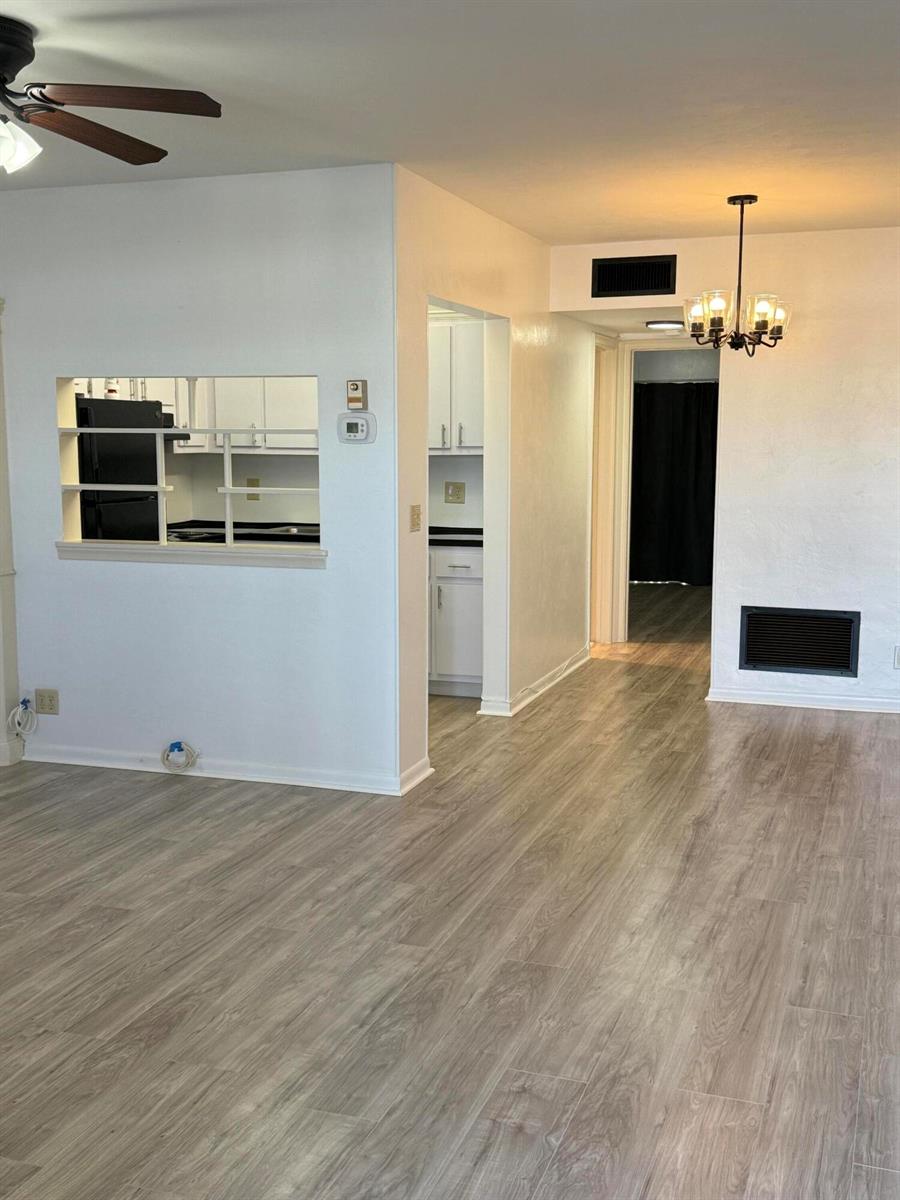 A living area with light wood-look flooring, a kitchen pass-through, and a dining room chandelier — 2960 Lake Osborne Drive # 209, FL 33461, FL