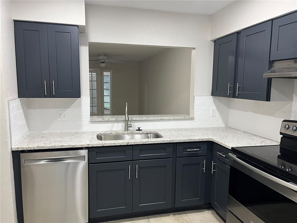 A kitchen features dark blue cabinets, granite countertops, stainless steel appliances, and white subway tile — 4372 MIDDLEBROOK ROAD UNIT 4372, ORLANDO, FL