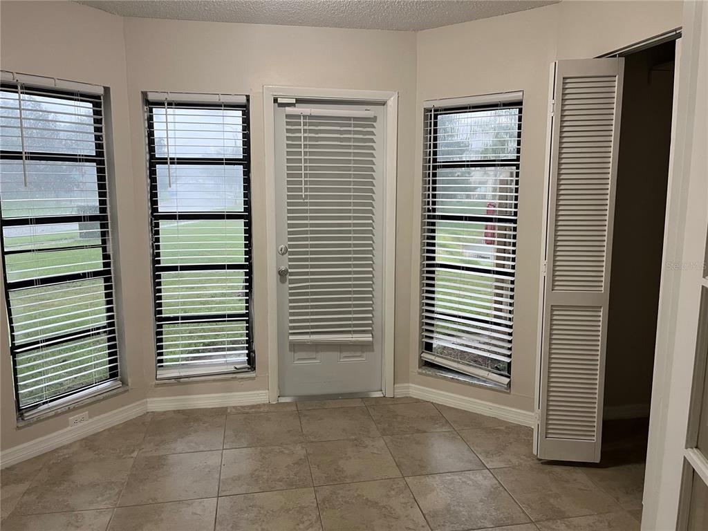 A room with tile flooring, three windows with blinds, a door, and a closet — 4372 MIDDLEBROOK ROAD UNIT 4372, ORLANDO, FL
