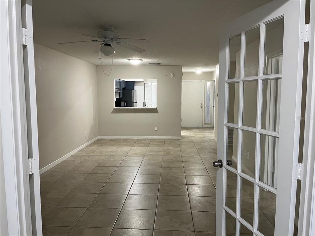 An interior view of a room with tiled floors, a ceiling fan, and a kitchen pass-through — 4372 MIDDLEBROOK ROAD UNIT 4372, ORLANDO, FL