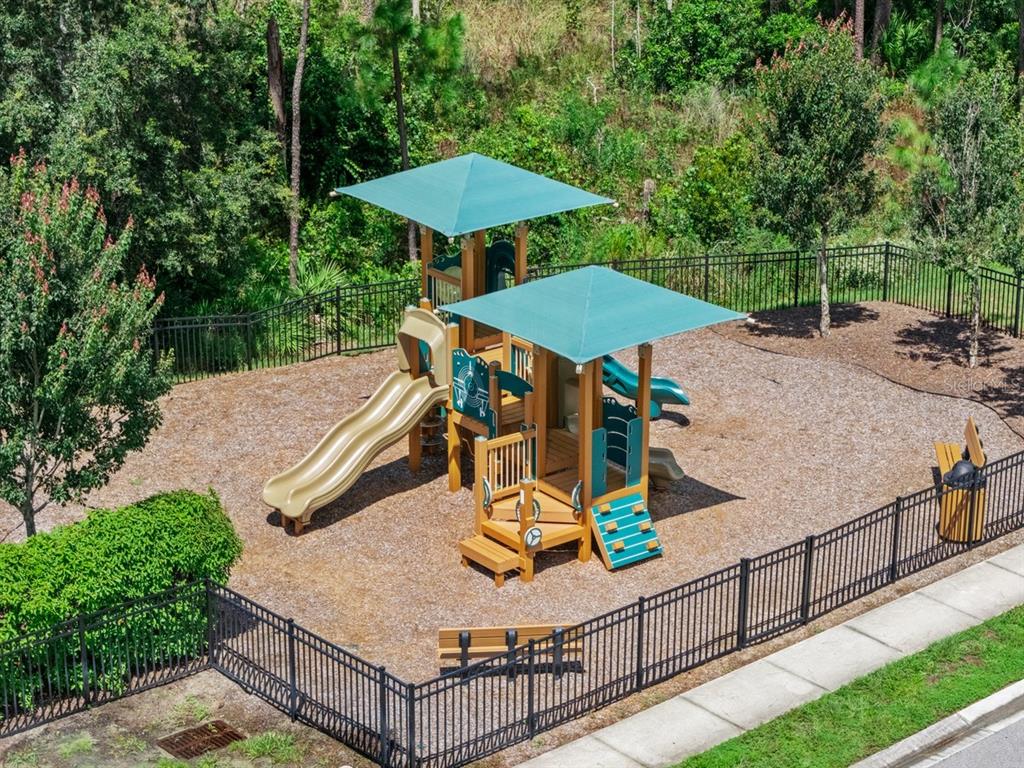 An aerial view of a fenced-in playground with two covered play structures and slides — 1437 SAWGRASS HAMMOCK LANE, DAVENPORT, FL