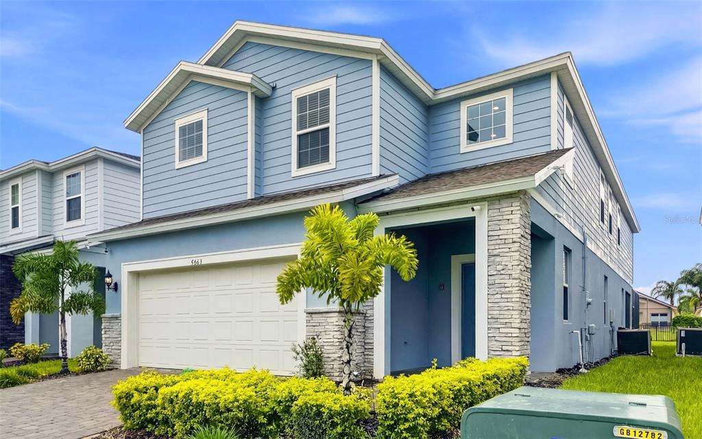 A two-story blue house with a two-car garage, stone accents, and a small palm tree — 4063 LANA AVENUE, DAVENPORT, FL