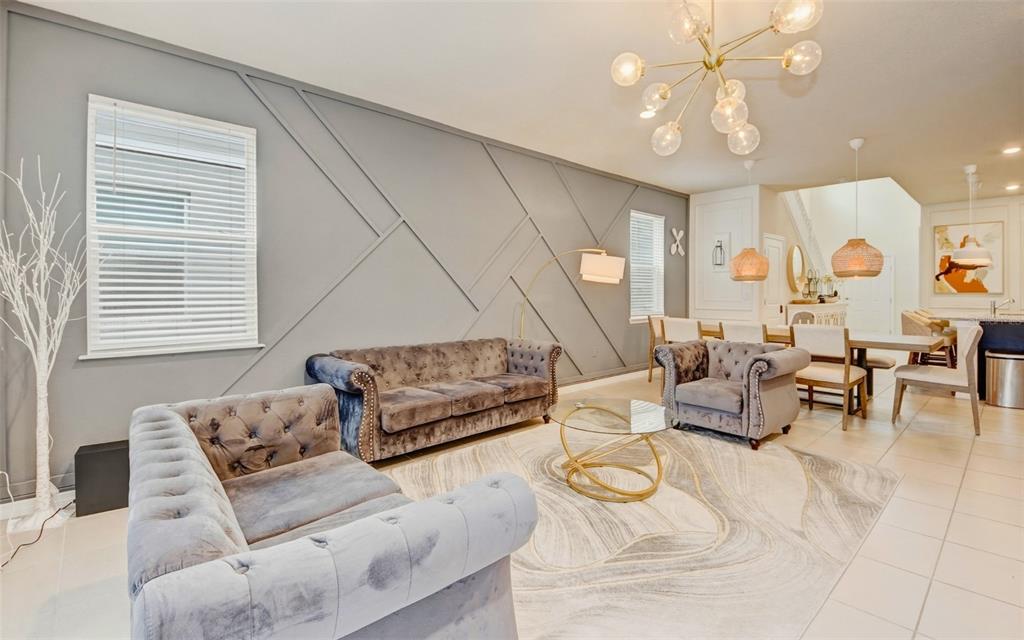 A living room features a gray accent wall with geometric molding, velvet furniture, and tile flooring — 4063 LANA AVENUE, DAVENPORT, FL