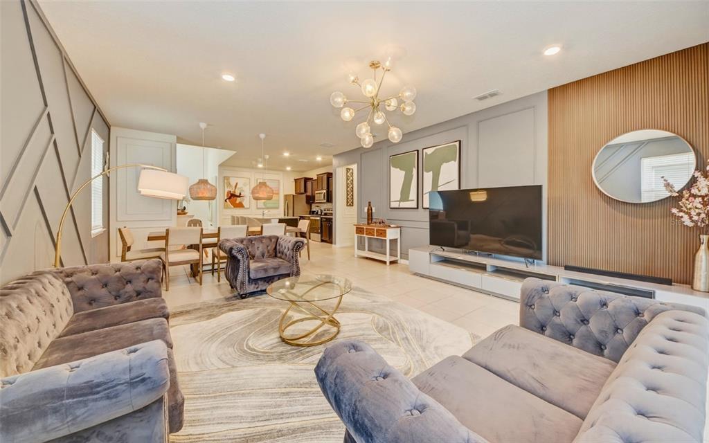 A living room with tufted grey sofas, a glass coffee table, and wood-slatted accent wall — 4063 LANA AVENUE, DAVENPORT, FL