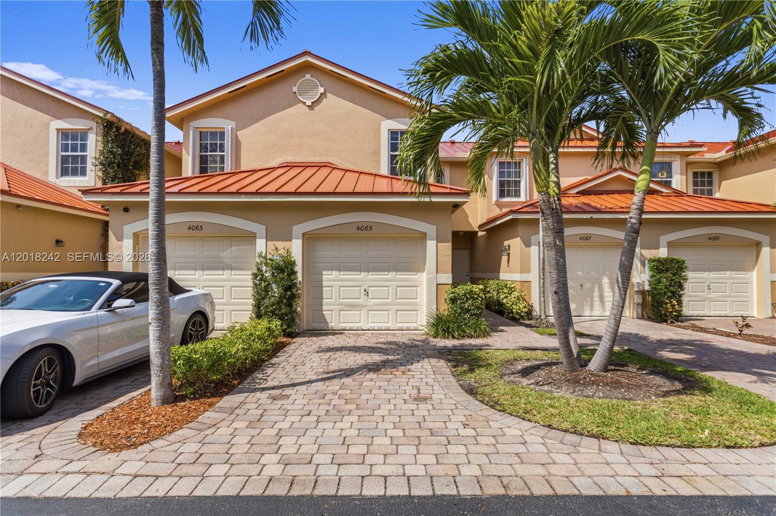 The exterior of a multi-unit residential building features tan stucco walls and orange metal roofs — 4065 Crystal Lake Dr, Deerfield Beach FL 33064, DEERFIELD BEACH, FL