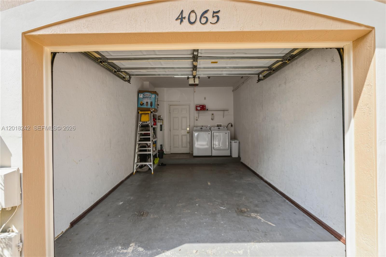 A garage interior features a concrete floor, a white door, and a laundry appliance set — 4065 Crystal Lake Dr, Deerfield Beach FL 33064, DEERFIELD BEACH, FL