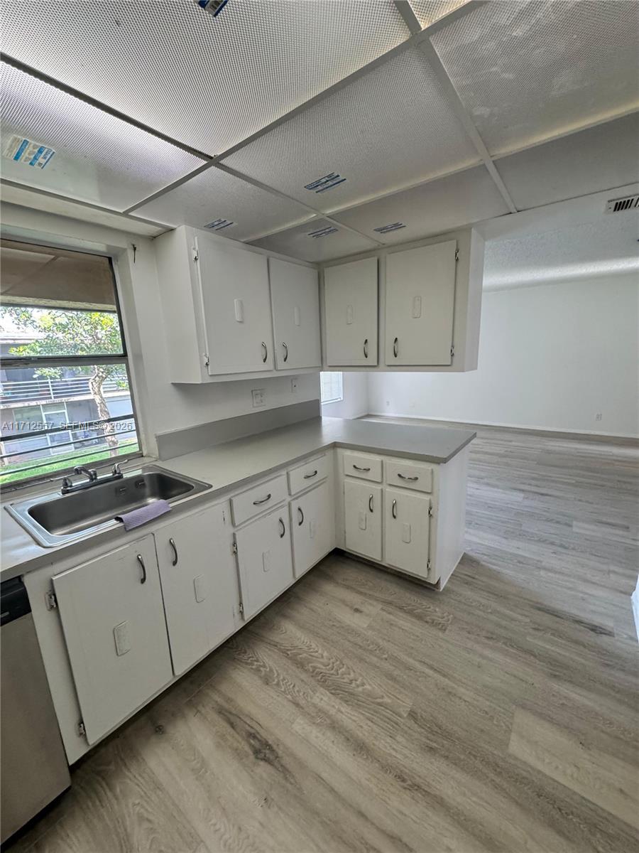 A kitchen with white cabinets, gray countertops, and light wood-look flooring — 4241 NW 19th St # 170, Lauderhill FL 33313, LAUDERHILL, FL